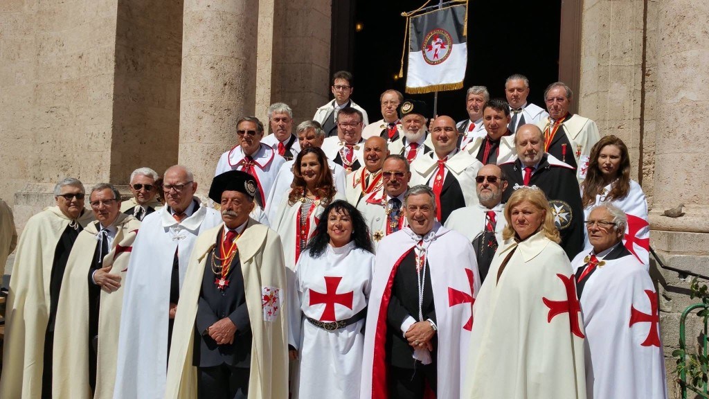 Photographie de groupe sur les marches de l’église, en manteaux blancs, avec la bannière de l’ordre