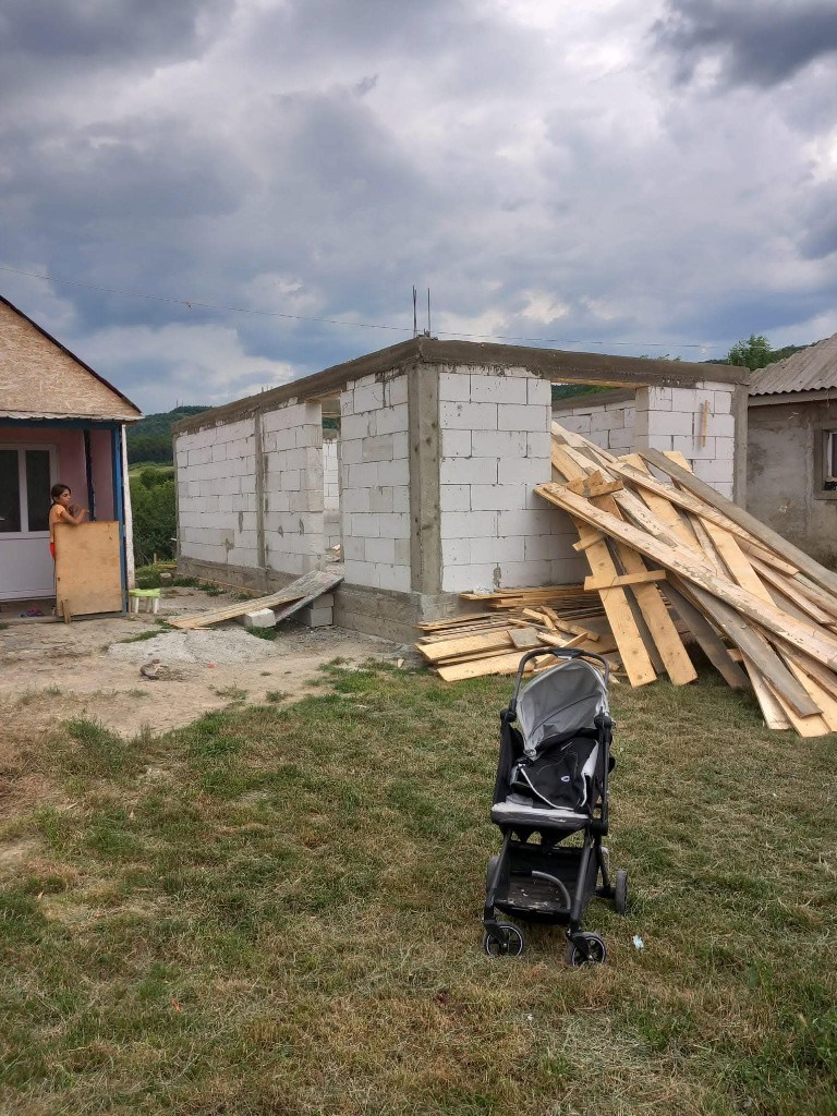 Chantier d’une maison nouvelle, avec une poussette au premier plan